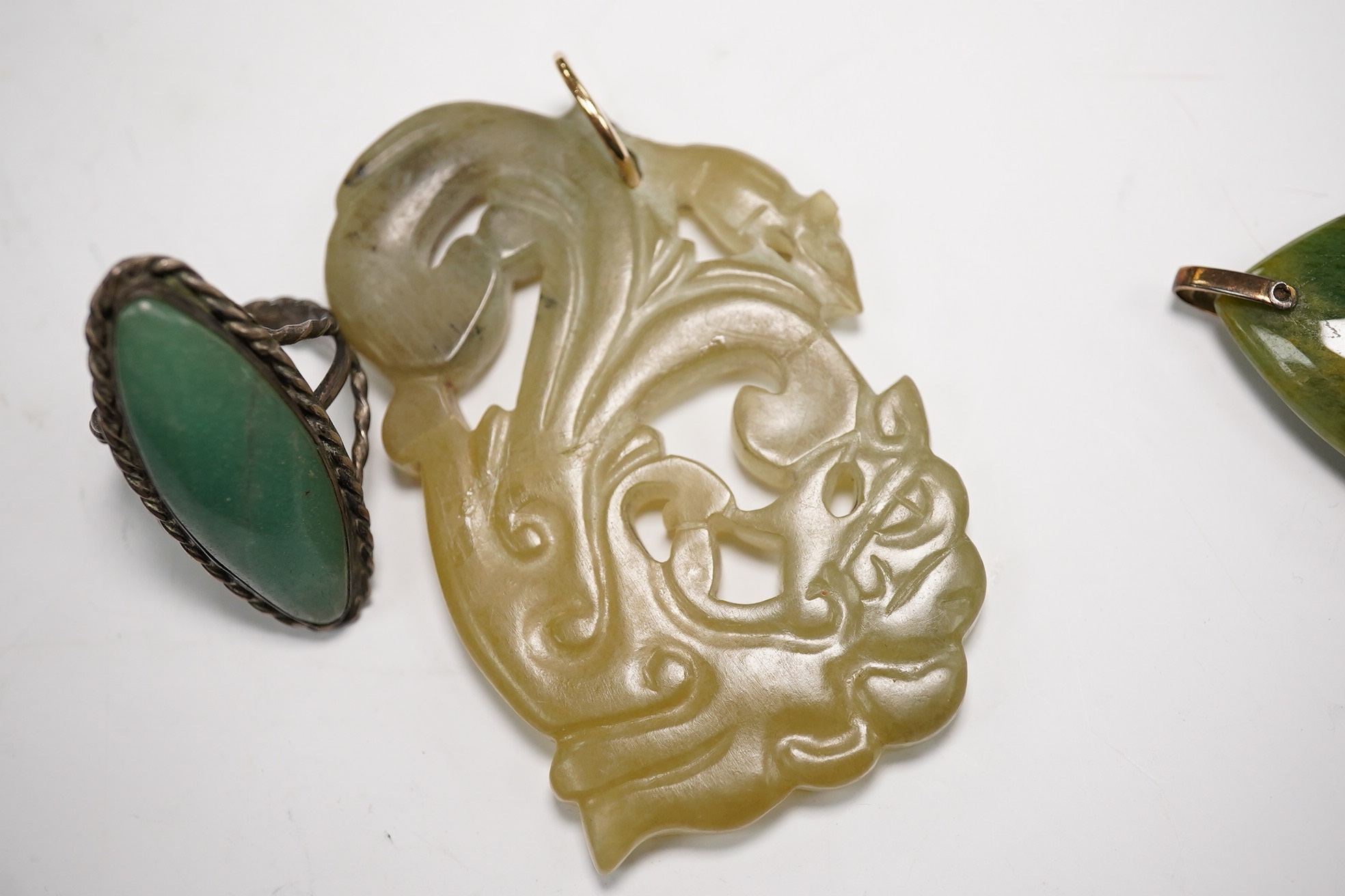 Two jade pendants including a carved example and a jade marquise ring, largest 6.5cm wide. Condition - fair to good